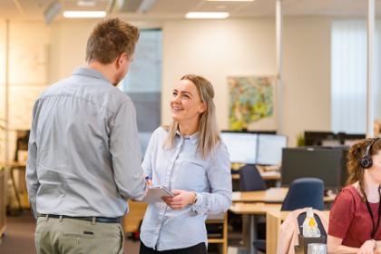 Uddannelse til finansøkonom var den rigtige vej Kvindelig finansøkonom fra EAMV står i bankmiljø og snakker glad med kollega